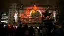 Masyarakat mengagumi instalasi seni bercahaya 'The Vision' karya seniman Portugis Ocubo yang diproyeksikan ke Hotel Queens di Kota Leeds, utara Inggris, 10 Oktober 2019. Festival mengambil alih jalanan pusat kota Leeds selama dua malam di bulan Oktober. (Oli SCARFF/AFP)
