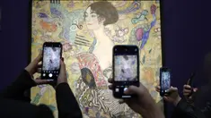 Orang-orang memotret 'Dame mit Faecher' (Lady with a Fan) karya Gustav Klimt saat dipajang di ruang lelang Sotheby's di London, Selasa (20/6/2023). (AP Photo/Kirsty Wigglesworth)
