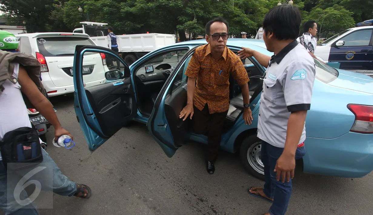 Para sopir taksi menurunkan penumpang sebuah taksi yang masih beroperasi saat aksi sweeping di Jalan Medan Merdeka Selatan, Jakarta, Senin (14/3). Ribuan sopir taksi dan bus kota menggelar unjuk rasa di Istana hari ini. (Liputan6.com/Immanuel Antonius)
