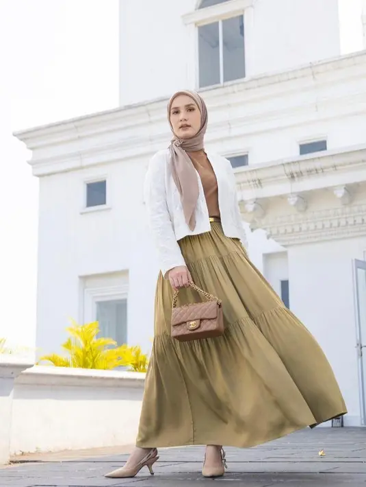 Tampil elegan, Dwi Handayani tampak memadukan tiered skirt nuansa warna kuning dengan cropped jacket warna putih dan t-shirt warna coklat sebagai inner. Untuk hijabnya, ia memilih hijab segi empat nuansa warna coklat. (Instagram/dwihandaanda).