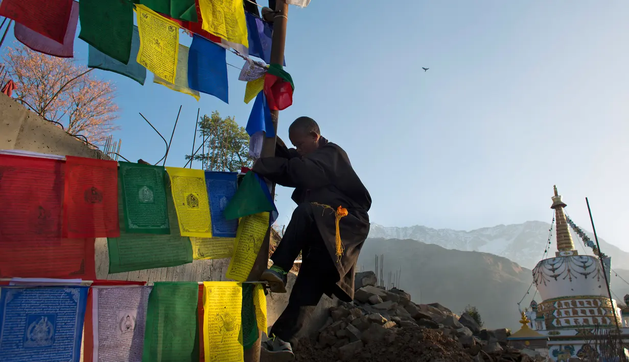 Seorang pria turun dari tiang usai memasang bendera warna-warni atau yang disebut lungta pada hari ketiga Tahun Baru Tibet di Dharmsala, India (18/2). (AP/Ashwini Bhatia)