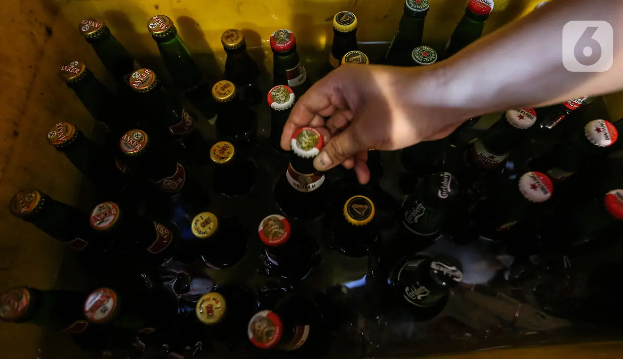 Pekerja mengambil botol minuman keras atau miras dari wadah penyimpanan di kafe kawasan Jakarta Selatan, Selasa (2/3/2021). Aturan yang diteken oleh Presiden Joko Widodo pada 2 Februari 2021 terkait memperbolehkan masyarakat untuk berinvestasi di produk miras dicabut. (Liputan6.com/Johan Tallo)