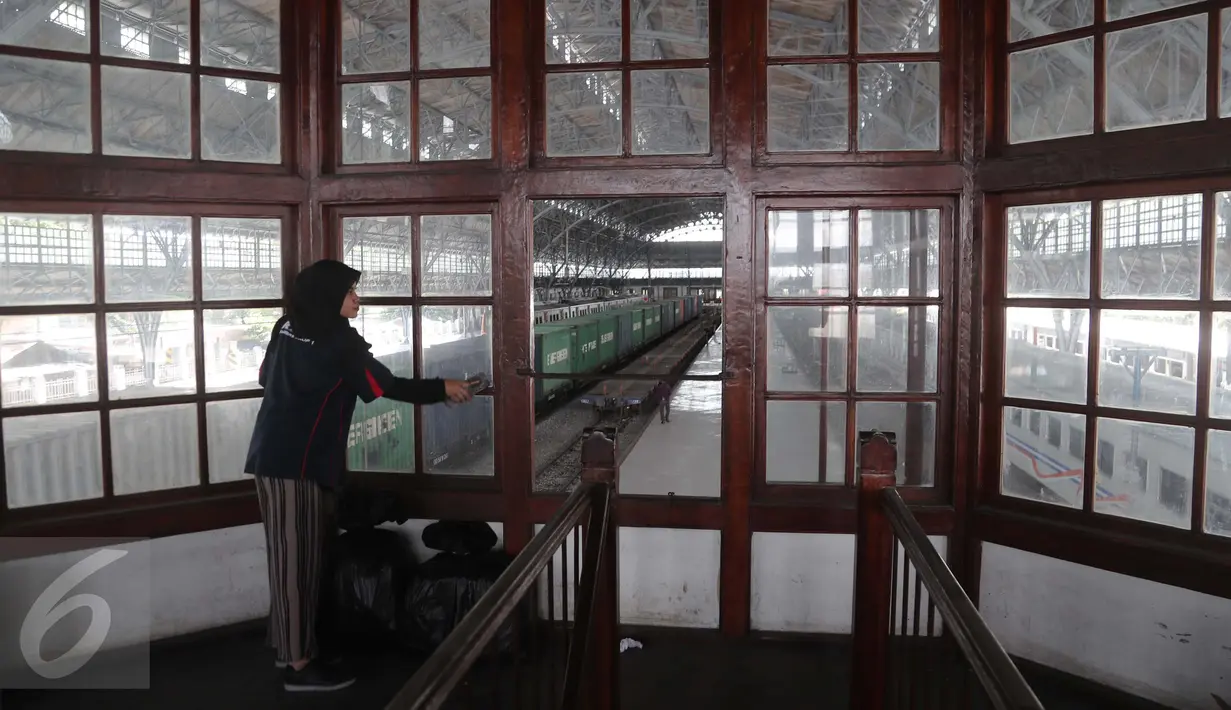 Seorang wanita dari komunitas Pecinta Kereta Api RD One membersihkan kaca jendela gedung di Stasiun Tanjung Priok, Jakarta Utara, Kamis (6/4). (Liputan6.com/Gempur M. Surya)