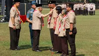 Wakil Presiden Ma`ruf Amin (tengah) didampingi Ketua Kwartir Nasional (Kwarnas) Pramuka Budi Waseso (kiri) menyematkan tanda penghargaan kepada anggota Pramuka di Bumi Perkemahan dan Graha Wisata (Buperta) Cibubur, Jakarta, Rabu (14/8/2024). (Liputan6.com/Herman Zakharia)