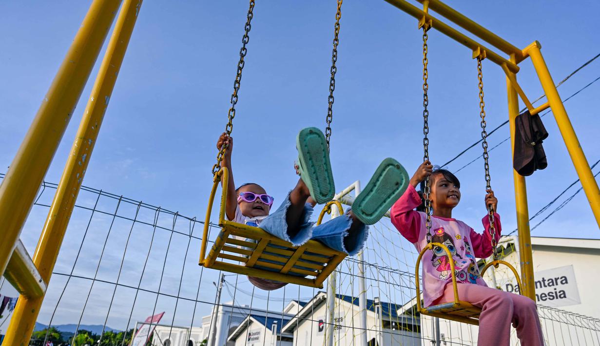 Safrizal ZA juga mengatakan seluruh unit huntara tersebut telah rampung dibangun dan siap dimanfaatkan oleh masyarakat penerima manfaat. Tampak dalam foto, anak-anak bermain ayunan di taman bermain di perumahan sementara yang dibangun oleh Badan Pengelola Investasi Daya Anagata Nusantara (Danantara) untuk para korban banjir di Meureudu, Kabupaten Pidie Jaya, provinsi Aceh, pada Minggu 22 Februari 2026, setelah banjir dan tanah longsor dahsyat melanda Sumatra, akhir tahun lalu. (CHAIDEER MAHYUDDIN/AFP)
