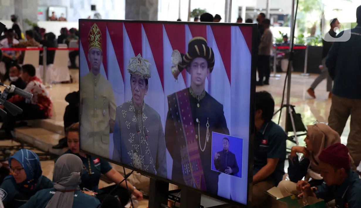 Layar televisi memperlihatkan pidato kenegaraan Presiden Joko Widodo atau Jokowi dalam Sidang Tahunan MPR, DPR, DPD di Gedung Nusantara, Jakarta, Selasa (16/8/2022). Di Gedung Nusantara, Presiden Jokowi akan menyampaikan pidato pada Sidang Tahunan MPR RI Tahun 2022 dan pidato kenegaraan dalam rangka Hari Ulang Tahun (HUT) ke-77 Kemerdekaan RI pada Sidang Bersama DPR RI dan DPD RI Tahun 2022. (Liputan6 com/Angga Yuniar)