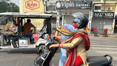 Seorang pengendara wanita menutupi kepala putrinya dengan syal untuk melindunginya dari panas yang menyengat di Lucknow, India, Sabtu, 18 Mei 2024. (AP Photo/Rajesh Kumar Singh)