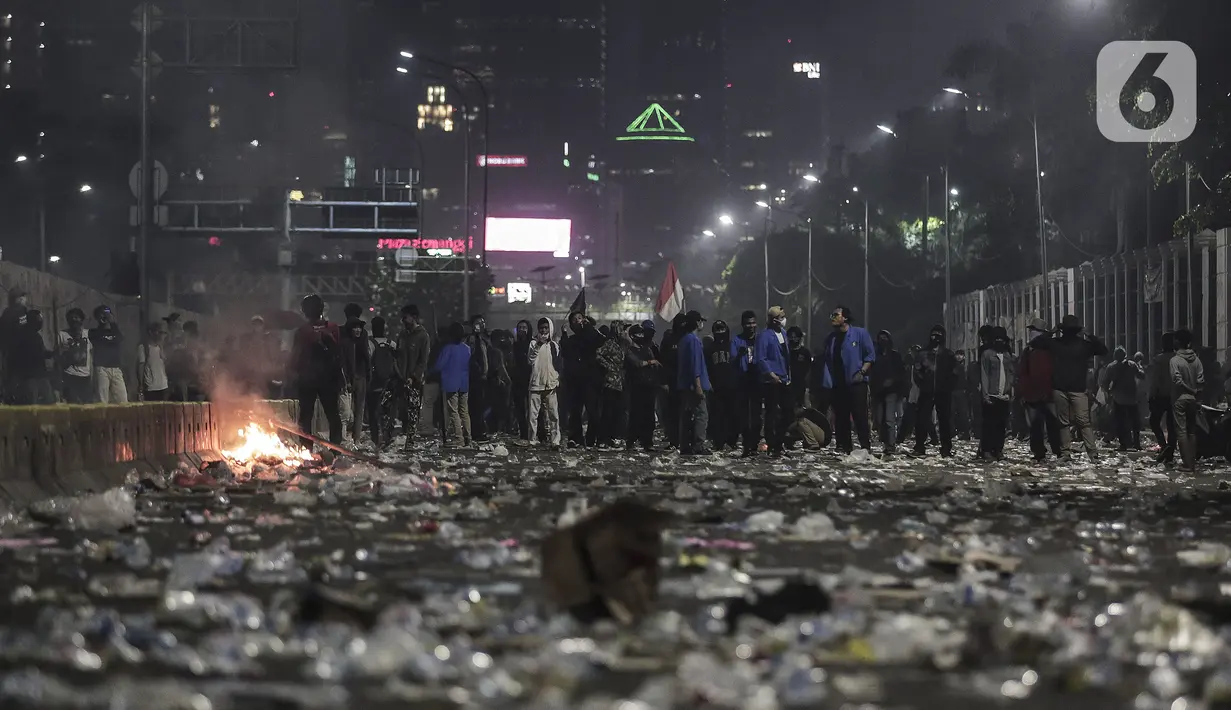 Mahasiswa dan elemen buruh bertahan hingga malam saat aksi di depan Gedung DPR/MPR/DPD, Jakarta, Kamis (16/7/2020). Dalam aksinya, mereka menolak pengesahan RUU Cipta Kerja atau Omnibus Law yang saat ini sedang dibahas DPR bersama pemerintah. (Liputan6.com/Johan Tallo)
