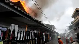 Petugas pemadam kebakaran berusaha memadamkan api yang membakar pemukiman penduduk di kawasan Pasar Kembangan, Senen, Jakarta, Senin(19/1/2015).  (Liputan6.com/Miftahul Hayat)