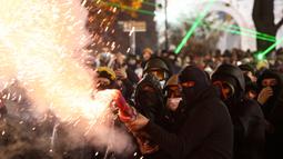 Pengunjuk rasa berkumpul di luar gedung parlemen pada Sabtu (30/11/2024) malam, melemparkan batu dan menyalakan kembang api. (Giorgi ARJEVANIDZE/AFP)