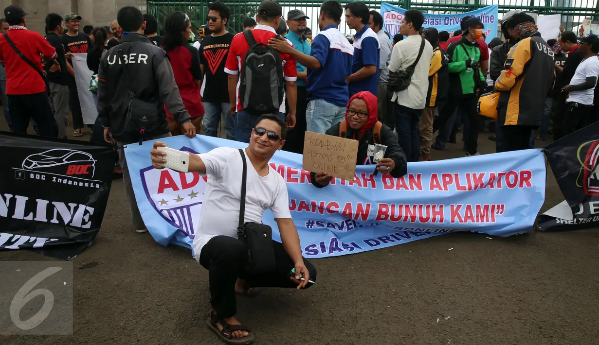 Dua orang pria berselfie saat menggelar unjuk rasa di depan Gedung MPR/DPR, Jakarta, Senin (27/2). Unjuk rasa tersebut memprotes kebijakan-kebijakan yang merugikan mereka. (Liputan6.com/Johan Tallo)