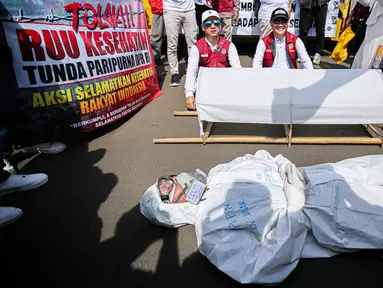 Pengunjuk rasa dari tenaga medis dan kesehatan melakukan aksi teatrikal di depan gedung MPR/DPR-DPD, Senayan, Jakarta, Selasa (11/7/2023). (Liputan6.com/Faizal Fanani)