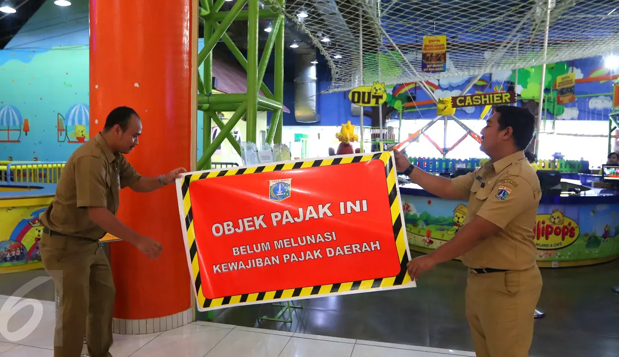 Dinas Pelayanan Pajak DKI memasang stiker penunggak pajak di wahana bermain anak di pusat perbelanjaan di kawasan Senayan, Jakarta, Senin (5/9). Pemasangan stiker dilakukan lantaran wajib pajak tempat usaha itu menunggak pajak. (Liputan6.com/Angga Yuniar)