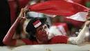 Seorang suporter Timnas Indonesia mengibarkan bendera Merah-Putih saat mendukung tim Garuda melawan Vietnam pada laga Semifinal AFF Cup 2016 di Stadion Pakansari, Bogor, (03/12/2016). (Bola.com/Nicklas Hanoatubun)