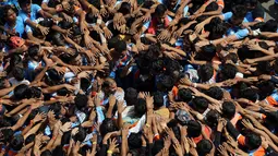 Umat Hindu membentuk piramida manusia selama Festival Janmashtami di Mumbai, India, 24 Agustus 2019. Piramida manusia itu untuk memecahkan pot berisikan suus yang menggangtung di langit-langit rumah supaya bisa diambil isinya. (AP Photo/Rajanish Kakade)