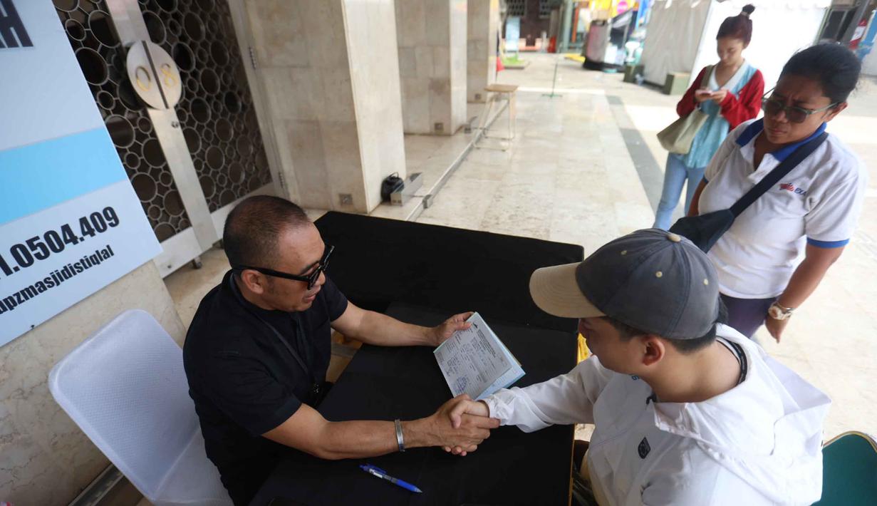 Zakat fitrah juga dapat ditunaikan dengan uang yang nilainya disetarakan dengan harga beras atau makanan pokok seberat 2,5 kg/3,5 liter atau yang biasa dikonsumsi sehari-hari. Tampak dalam foto, petugas Unit Pengelola Zakat (UPZ) melayani pembayaran zakat, fidyah, kafarat, infaq, dan shadaqah di teras Masjid Istiqlal, Jakarta, Minggu 15 Maret 2026. (Kapanlagi.com/Budy Santoso)