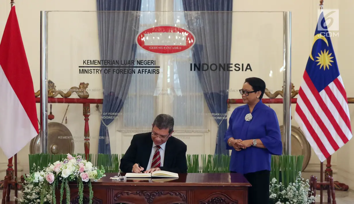 Menteri Luar Negeri Malaysia, Dato' Saifuddin Abdullah (kiri) didampingi Menteri Luar Negeri RI Retno Marsudi menandatangani buku tamu jelang pertemuan  di Gedung Pancasila, Jakarta, Senin (23/7). (Liputan6.com/Helmi Fithriansyah)