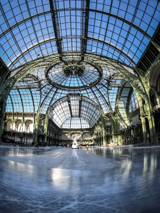 Sebuah  arena ice skating di bawah kubah kaca mewah legendaris, Grand Palais, Paris, Senin (17/12). Arena ice skating musiman ini terbuka untuk umum selama liburan Natal. (STEPHANE DE SAKUTIN / AFP)