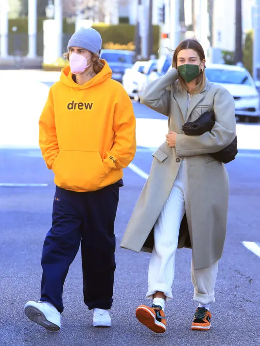 Tertangkap kamera sedang menikmati waktu berdua, Justin terlihat tampil dengan gaya kasualnya dalam hoodie oranye dari Drew House, serasi dengan warna sneakers Hailey yang tampil mengenakan long coat cokelat muda.