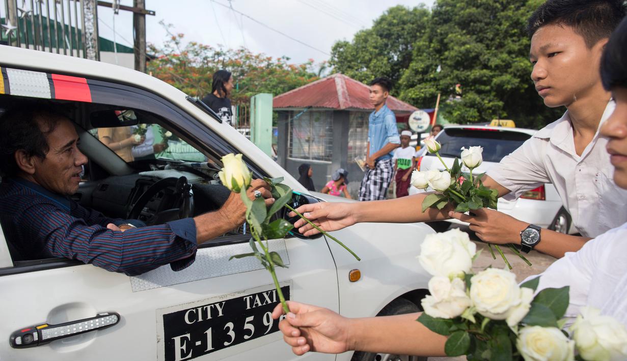 Umat Buddha Myanmar memberikan mawar putih kepada umat Islam yang akan melaksanakan salat Id pada perayaaan Idul Fitri di kota Than Lyin, Yangon, Rabu (5/6/2019). Tindakan itu dilakukan beberapa minggu setelah kelompok garis keras berusaha menghapuskan doa selama bulan Ramadhan. (Sai Aung MAIN/AFP)