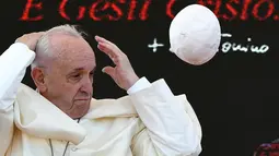 Paus Fransiskus memegang kepala saat menghadiri upacara peringatan 25 tahun kematian Don Tonino Bello di Alessano, Italia (20/4). Angin yang tiba-tiba bertiup membuat zucchetto yang dipakai Paus Fransiskus terbang dari kepalanya. (AFP/Vincenzo Pinto)