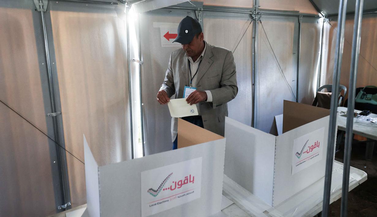 Pemilu berlangsung di bawah bayang-bayang pendudukan Israel, di mana tentara Israel terus memperketat kontrol dan terjadi perpindahan paksa warga Palestina, terutama di wilayah seperti Jenin dan Tulkarem. Tampak dalam foto, seorang pria Palestina bersiap untuk memberikan suara di Tempat Pemungutan Suara (TPS) selama pemilihan kota di Deir el-Balah, Jalur Gaza, pada Sabtu 25 April 2026. (Eyad Baba/AFP)