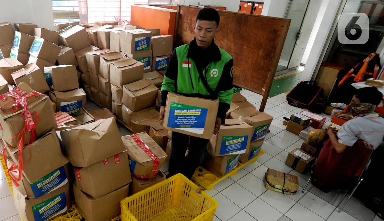 Pengemudi ojek online mengemas bansos untuk warga yang terdampak COVID-19 di Kantor Pos, Cibinong, Bogor, Jawa Barat, Senin (20/4/2020). Pemprov Jabar menyalurkan bansos senilai Rp 500 ribu bagi warga berpenghasilan rendah dan termasuk miskin baru akibat pandemi COVID-19. (merdeka.com/Arie Basuki)