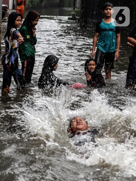 Anak-anak bermain air saat banjir merendam lingkungan rumah tempat tinggal mereka di kawasan kecamatan Kebayoran Baru, Jakarta, Senin (25/01/2021). Hujan deras yang mengguyur Jakarta hari ini, Senin (25/1) menyebabkan terjadinya banjir di kawasan permukiman tersebut. (Liputan6.com/Johan Tallo)