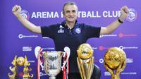 Pelatih Arema FC, Milomir Seslija, bersama trofi yang pernah diraih di Arema musim 2016 dan 2019. (Bola.com/Iwan Setiawan).