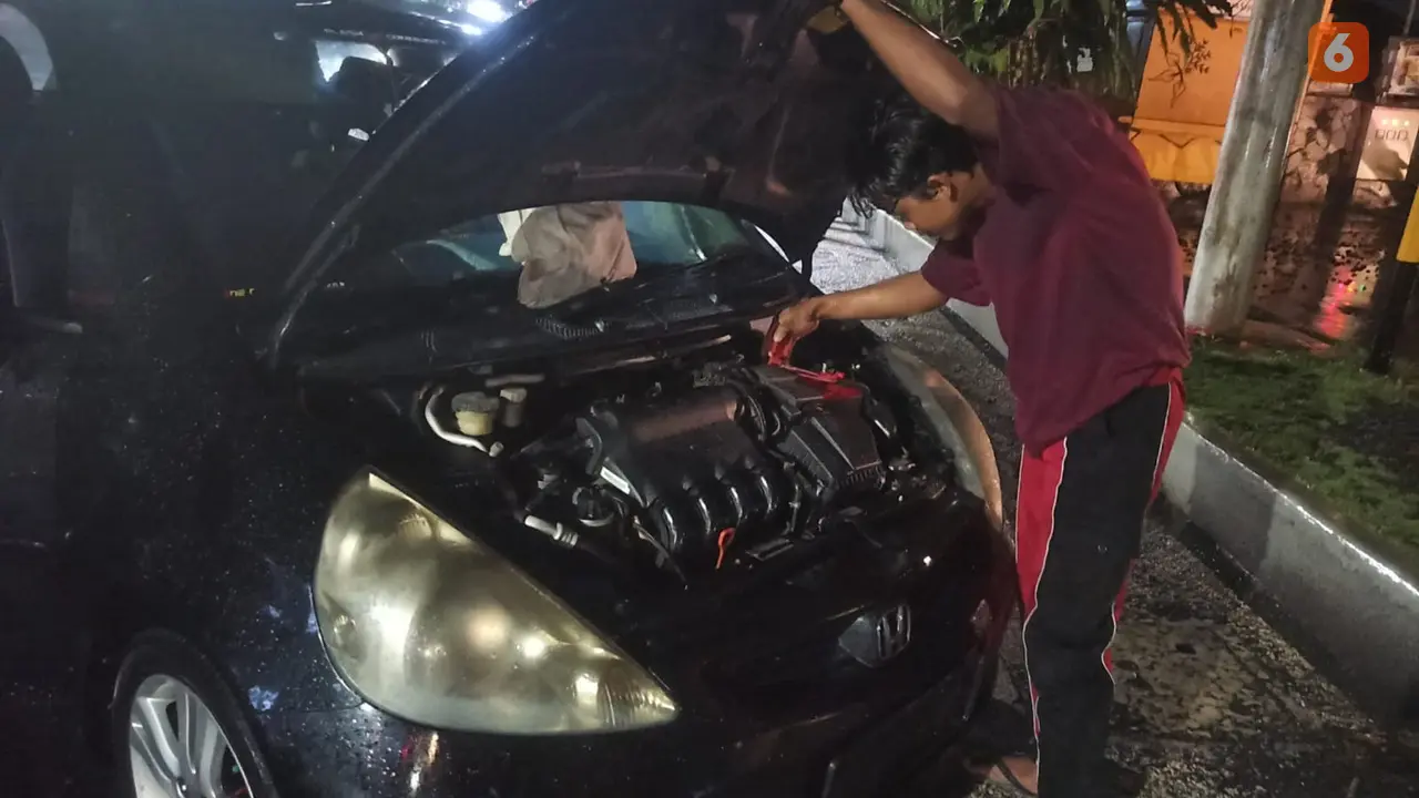 Pemilik bengkel di Banyuwangi Ardi, memperbaiki mobil mogok akibat terendam banjir. (Hermawan Arifianto/Liputan6.com)
