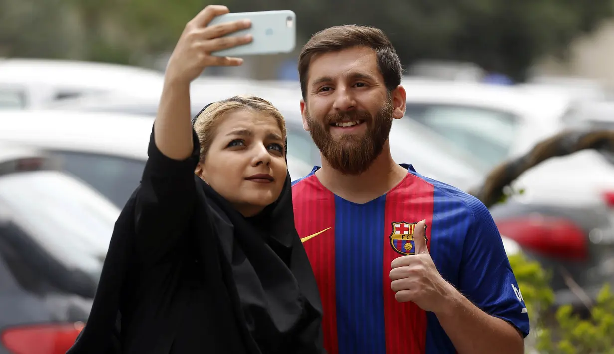 Reza Parastesh, seorang warga Iran yang memiliki wajah mirip Lionel Messi diajak selfie oleh warga di jalanan Tehran, Iran, Senin (8/5/2017). (AFP/Atta Kenare)