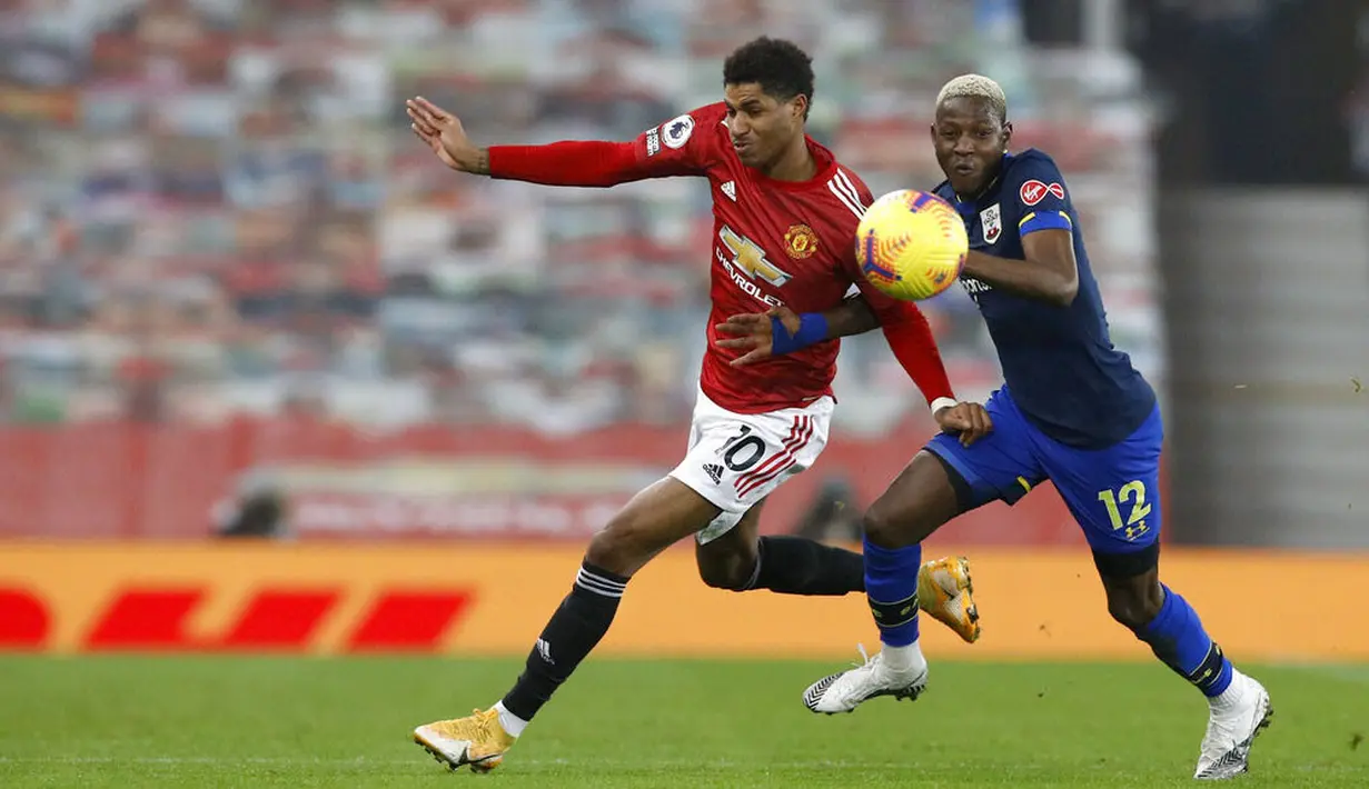 Striker Manchester United, Marcus Rashford, berebut bola dengan pemain Southampton, Moussa Djenepo, pada laga Liga Inggris di Stadion Old Trafford, Selasa (2/2/2021). Setan Merah menang dengan skor 9-0. (Phil Noble/Pool via AP)
