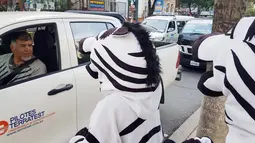 Warga berpakaian seperti zebra berbincang dengan pengendara mobil saat program pendidikan di jalan di La Paz, Bolivia,(5/12). Kegiatan ini untuk meningkatkan kesadaran masyarakat tentang keselamatan di jalan. (REUTERS/David Mercado)