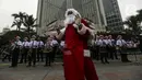 Seorang berpakaian sinterklas berdiri di depan peserta yang sedang bermain angklung saat acara Christmas in Jakarta di Bundaran Hotel Indonesia, Jakarta, Selasa (21/12/2021). Pemerintah Provinsi DKI Jakarta menggelar Christmas in Jakarta dalam rangka menyambut Natal 2021. (Liputan6.com/Johan Tallo)