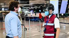 Petugas mengenakan termoscanner portabel "Smart-Helmet" untuk memeriksa suhu penumpang dan sesama staf di terminal keberangkatan bandara Fiumicino Roma, Italia pada 5 Mei 2020. Hal ini dilakukan guna menyaring orang yang memiliki gejala infeksi virus corona. (ANDREAS SOLARO/AFP)