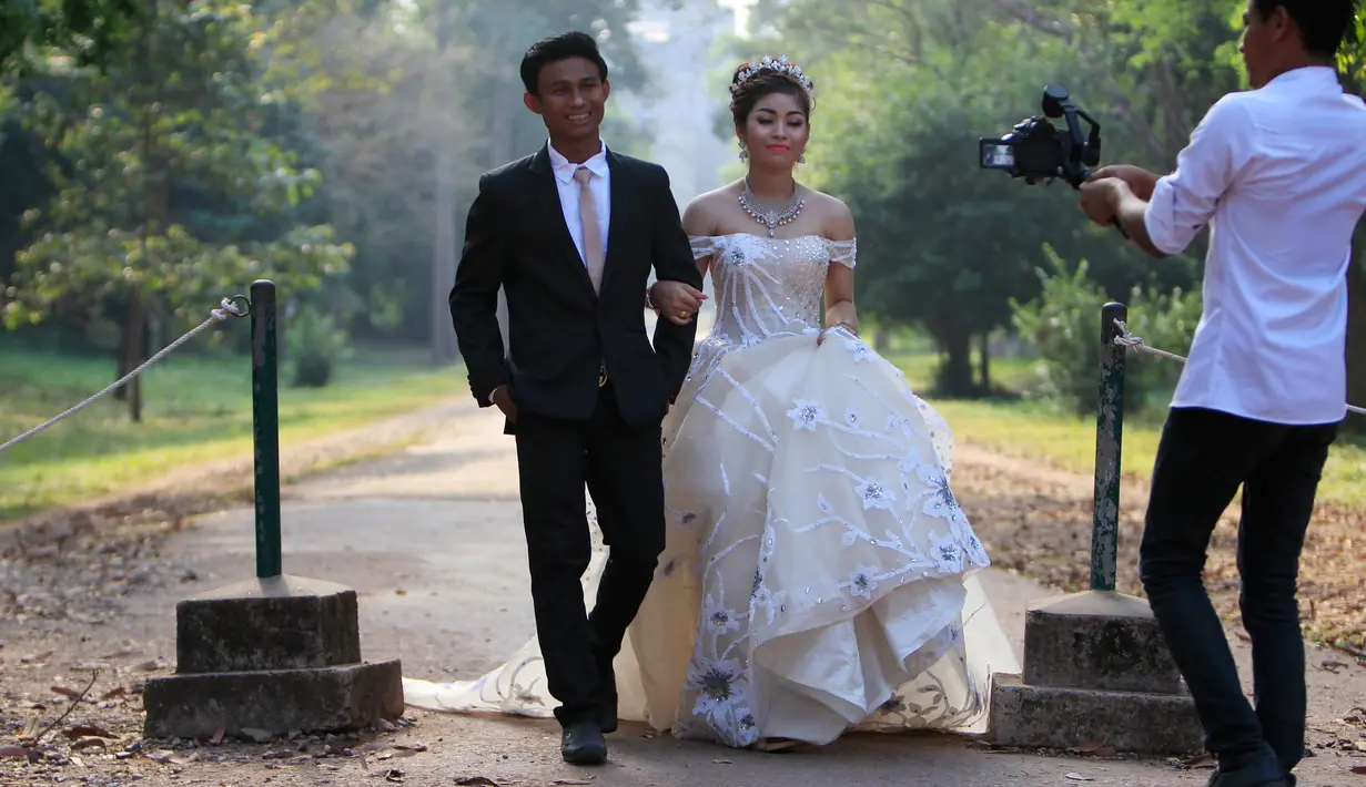 Sepasang pengantin baru melakukan foto pernikahan mereka di kompleks kuil Angkor Wat, sebuah candi ikonik dan bersejarah di Kamboja, 14 Maret 2018. Candi ini adalah jantung dan jiwa Kamboja serta menjadi kebangaan nasional. (AP Photo/Heng Sinith)