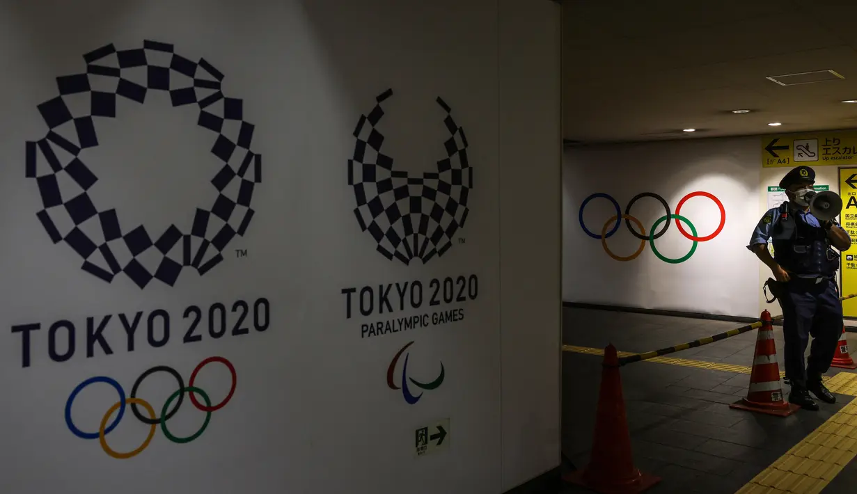 Seorang polisi berbicara menggunakan megafon dekat Stadion Olimpiade jelang upacara pembukaan Olimpiade Tokyo 2020, di Tokyo, Jelang, Jumat (23/7/2021).  Upacara pembukaan Olimpiade Tokyo 2020 akan digelar pada 23 Juli 2021 malam. (Yuki IWAMURA/AFP)