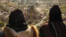 Para perempuan Palestina menyaksikan pasukan Israel yang menggunakan ekskavator merobohkan sebuah bangunan yang dibangun tanpa izin di lingkungan Wadi Qaddum, Yerusalem timur, pada Senin 22 Desember 2025. Ratusan warga Palestina terusir saat buldoser-buldoser Israel meratakan sebuah bangunan tempat tinggal empat lantai di wilayah Yerusalem Timur. (Ahmad GHARABLI/AFP)