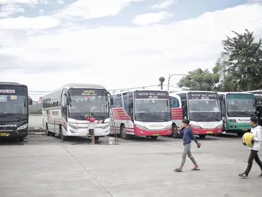 Dua pria melintasi bus yang terparkir di Terminal terpadu tipe A Pondok Cabe di Pamulang, Tangerang Selatan, Senin (31/12). Mulai 31 Desember , terminal yang memiliki luas mencapai 25.995 m2 tersebut resmi beroperasi. (Liputan6.com/Faizal Fanani)