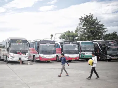 Dua pria melintasi bus yang terparkir di Terminal terpadu tipe A Pondok Cabe di Pamulang, Tangerang Selatan, Senin (31/12). Mulai 31 Desember , terminal yang memiliki luas mencapai 25.995 m2 tersebut resmi beroperasi. (Liputan6.com/Faizal Fanani)