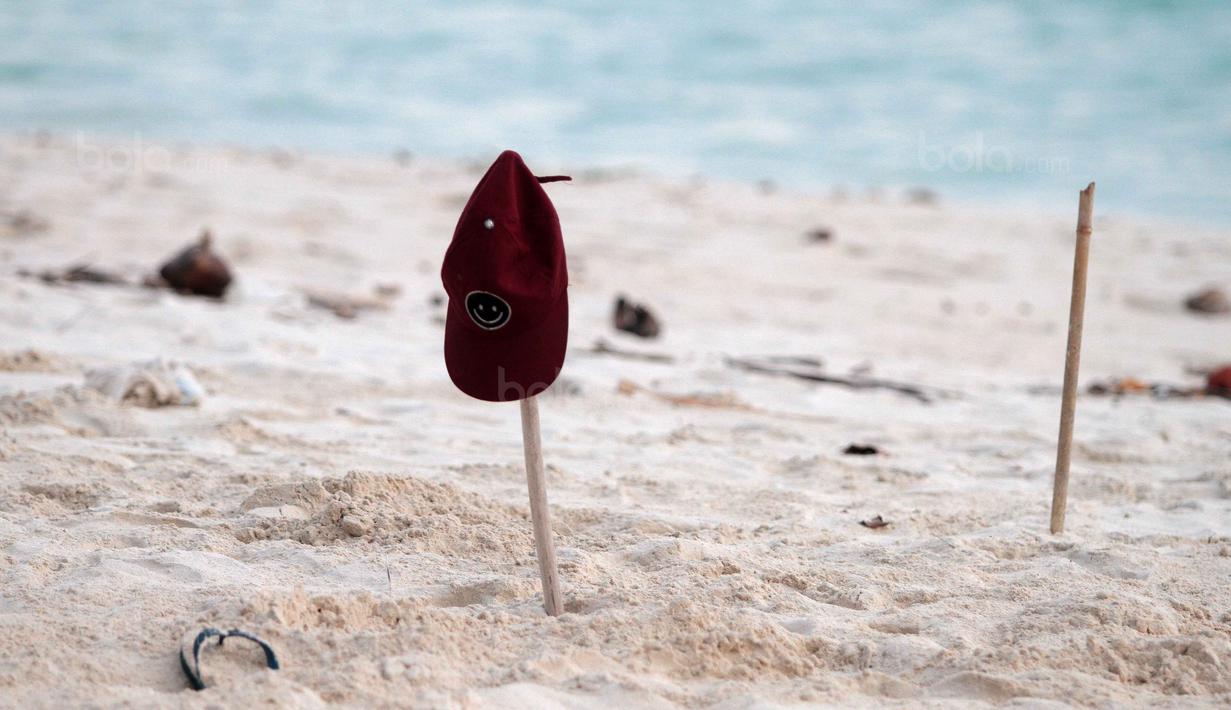 Topi dan kayu sebagai tanda gawang saat bermain bola dekat pantai di Desa Matwaer, Kei Kecil, Maluku (25/12/2017). Bermain bola di pasir menjadi daya tarik tersendiri bagi anak dan pmuda desa. (Bola.com/Nick Hanoatubun)