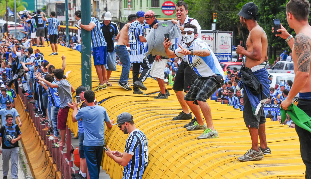 Suporter merayakan keberhasilan Gremio meraih juara Copa Libertadores di Porto Alegre, Brasil, Kamis (30/11/2017). Gremio menjadi juara Copa Libertadores setelah mengalahkan Lanus dengan skor agregat 3-1. (AFP/Itamar Aguiar)