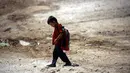Seorang anak pengungsi berjalan berangkat ke sekolah di sebuah kamp di Ain Issa, Suriah (22/8). Meski belajar di dalam tenda pengungsian, anak-anak tetap antusias mengikuti hari pertama tahun ajaran baru sekolah. (AFP Photo/Delil souleiman)