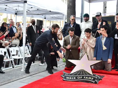 Kevin Jonas (berlutut dari kiri), Nick Jonas, dan Joe Jonas dari Jonas Brothers pada upacara penganugerahan bintang Hollywood Walk of Fame di Los Angeles, Amerika Serikat, 30 Januari 2023. Jonas Brothers menerima bintang ke-2.745 di Hollywood Walk of Fame. (Photo by Jordan Strauss/Invision/AP)