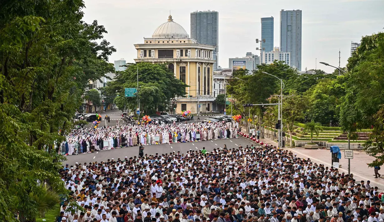 Penetapan ini juga merujuk pada Keputusan Musyawarah Nasional XXXII Tarjih Muhammadiyah tentang Kalender Hijriah Global Tunggal (KHGT). Tampak dalam foto, umat muslim saat melaksanakan salat Idul Fitri 1447 Hijriah di salah satu ruas jalan di kota Surabaya, Jawa Timur, pada Jumat 20 Maret 2026. (JUNI KRISWANTO/AFP)