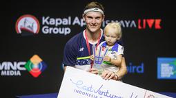 Pebulu tangkis tunggal putra Denmark, Viktor Axelsen, membawa anaknya saat merayakan gelar juara Indonesia Open 2022. (Bola.com/Bagaskara Lazuardi)