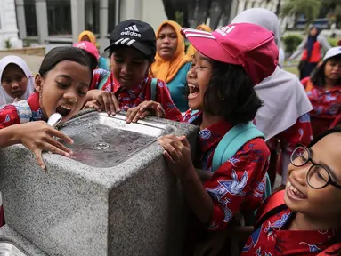 Anak-anak sekolah berebut air minum di fasilitas air siap minum (Drinking Fountain) di Museum Nasional, Jakarta, Kamis (8/11). Pembangunan drinking fountain ini untuk menyediakan air siap minum yang higienis bagi masyarakat. (Liputan6.com/Fery Pradolo)