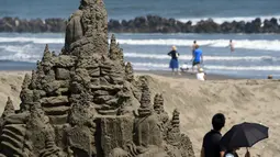 Pengunjung sedang menikmati pemandangan pantai diantara patung pasir di Yasashigaura, Pantai Asahi , Tokyo, Sabtu (11/7/2015). Pameran ini digelar mulai Senin (6/7) lalu. (AFP PHOTO/Toshifumi Kitamura)