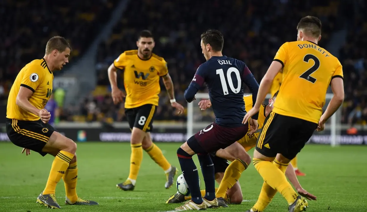 Mesut Ozil dikawal ketat oleh empat pemain Wolves pada laga lanjutan Premier League yang berlangsung di Stadion Molineux, Wolverhampton, Kamis (25/4). Arsenal kalah 1-3 kontra Wolves. (AFP/Paul Ellis)