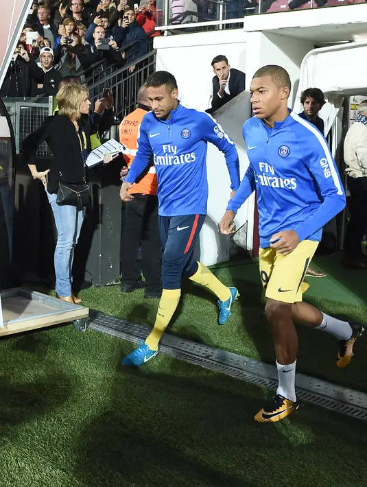 Penyerang PSG, Kylian Mbappe dan Neymar memasuki lapangan bersiap bertanding melawan Metz pada laga lanjutan Ligue 1 di stadion Longeville-les-Metz, Prancis (8/9). PSG menang 5-1 atas Metz. (AFP Photo/Patrick Hertzog)